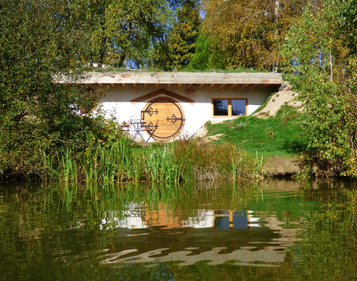 Hébergement insolite en Auvergne : maison ronde au bord de leau, entourée de verdure.