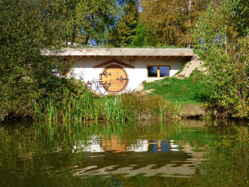 Hébergement insolite en Auvergne : maison ronde au bord de leau, entourée de verdure.