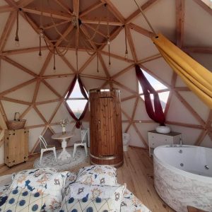 Dôme géodésique cosy avec baignoire ronde et décoration chaleureuse.
