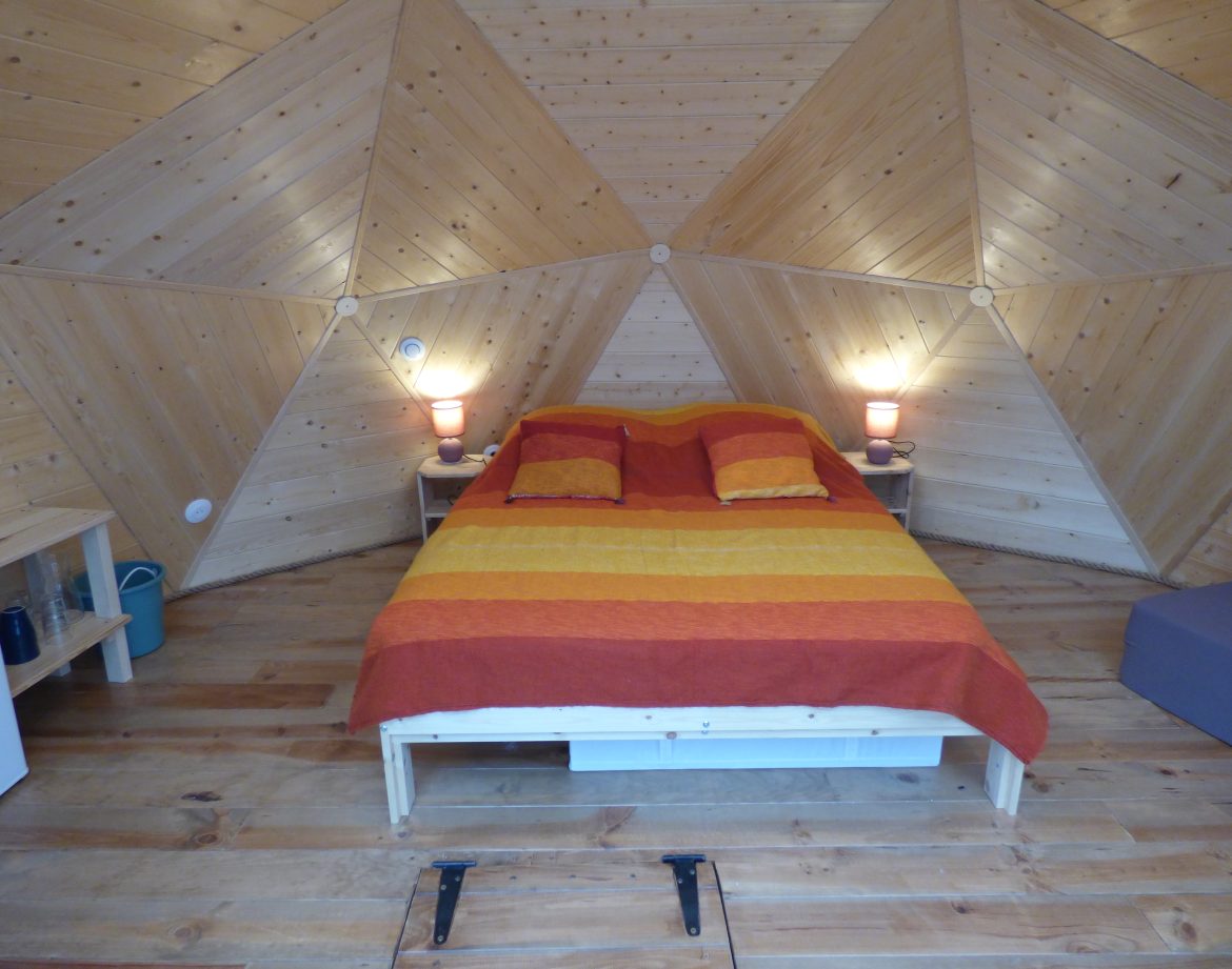 Chalet géodésique en Auvergne, avec un intérieur en bois et des couleurs chaleureuses.