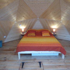 Chalet géodésique en Auvergne, avec un intérieur en bois et des couleurs chaleureuses.