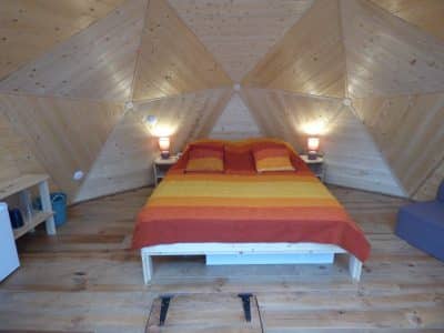 Chalet géodésique en Auvergne, avec un intérieur en bois et des couleurs chaleureuses.