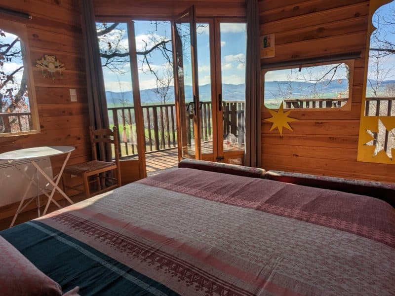 Chalet en bois avec vue panoramique et balcon, décoré de couleurs vives.