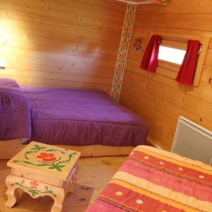 Chalet en bois coloré avec lits douillets et décorations artisanales.