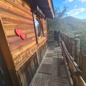 Cabane en bois en Corse avec un balcon et des cœurs décoratifs rouges.