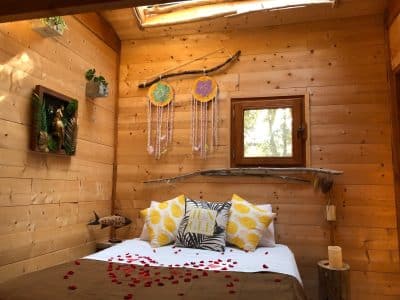 Chalet en bois avec décoration chaleureuse et pétales de rose sur le lit.