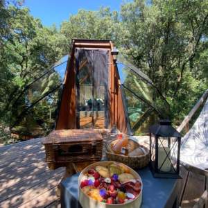 Cabane en bois avec vue sur la nature, petit-déjeuner gourmand en terrasse.
