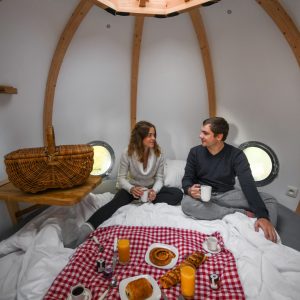 Hébergement insolite en forme de bulle, couple partageant un petit-déjeuner convivial.