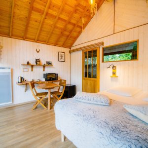 Cabane en bois cosy avec lit douillet et coin repas lumineux.