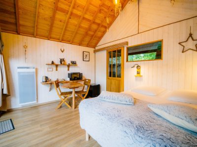 Cabane en bois cosy avec lit douillet et coin repas lumineux.
