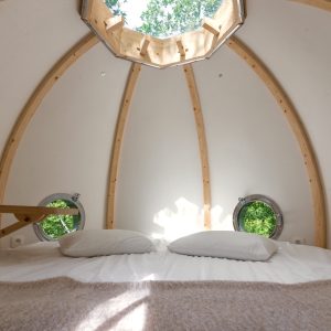 Hébergement insolite en forme de bulle, avec fenêtres rondes et vue sur la nature.