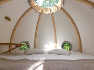 Hébergement insolite en forme de bulle, avec fenêtres rondes et vue sur la nature.