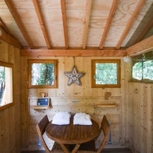 Cabane en bois cosy avec table ronde et décor en bois naturel. Parfait pour un séjour relaxant.