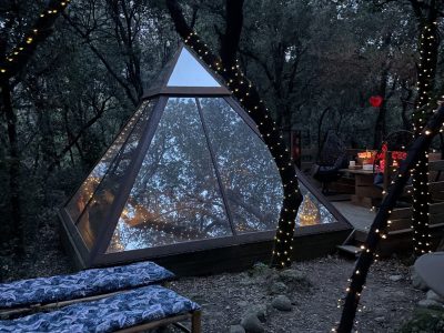 Tente pyramidale en bois, illuminée, nichée dans la forêt du Languedoc-Roussillon.
