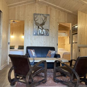 Chalet en bois chaleureux avec salon, fauteuils confortables et décoration naturelle.