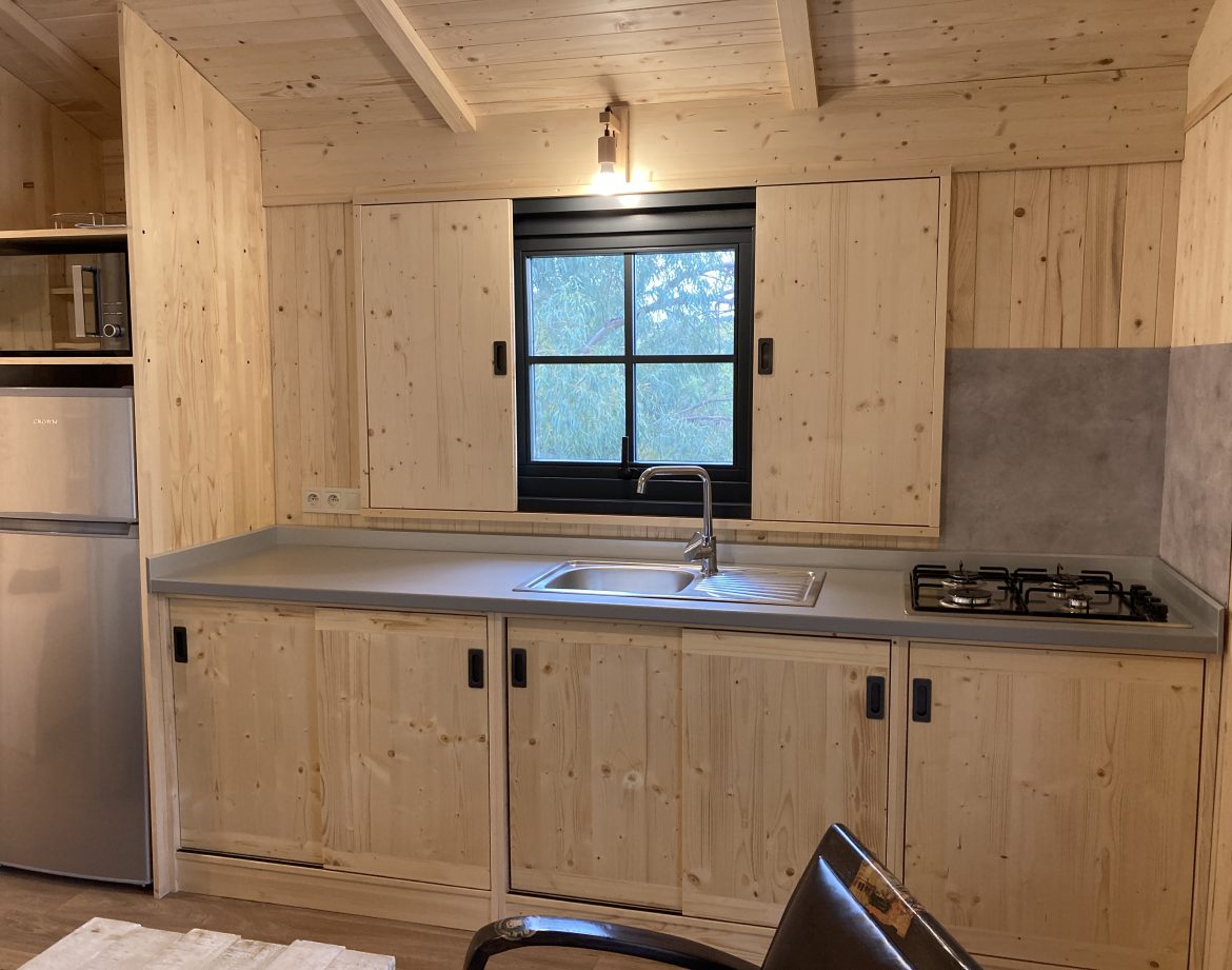 Cabane en bois dans le Languedoc-Roussillon, avec cuisine moderne et fenêtre lumineuse.