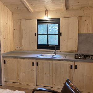 Cabane en bois dans le Languedoc-Roussillon, avec cuisine moderne et fenêtre lumineuse.