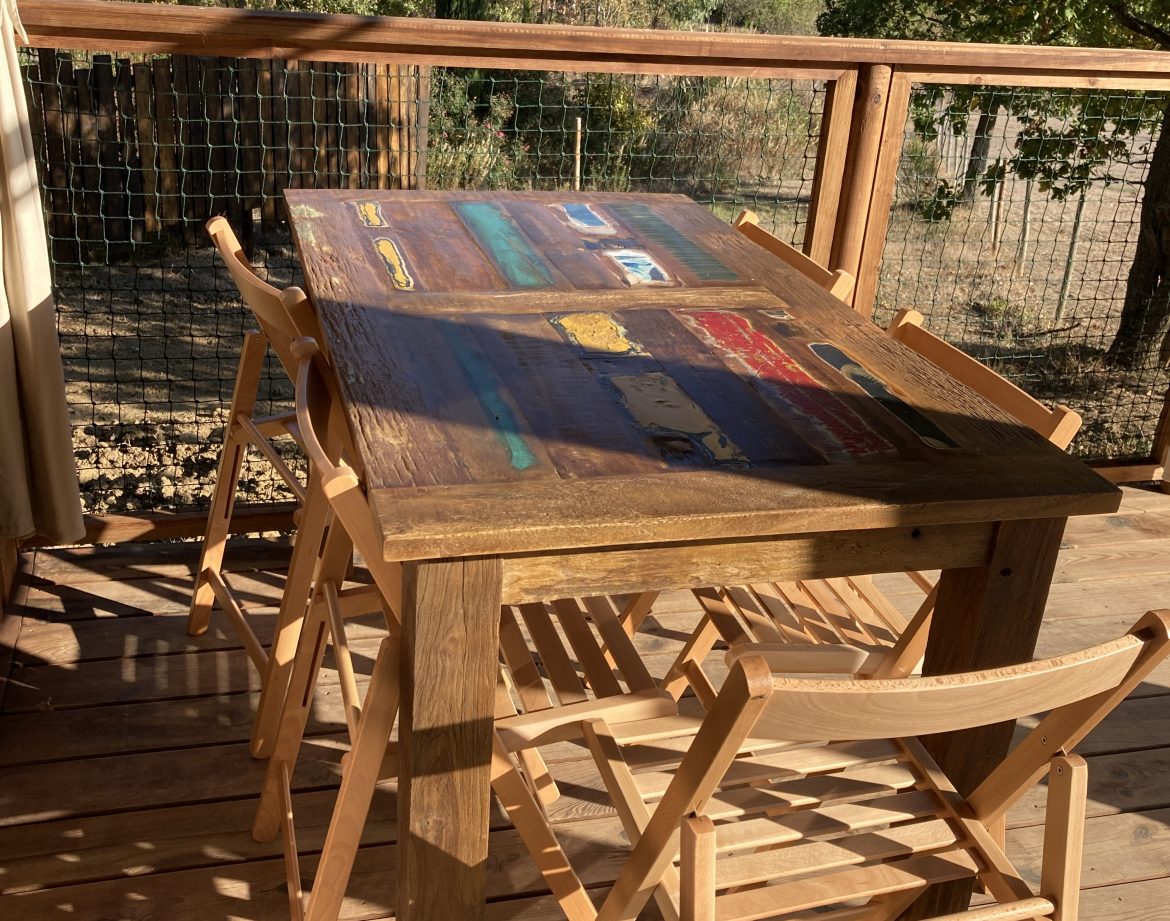 Table en bois sur une terrasse dun hébergement insolite en Languedoc-Roussillon.