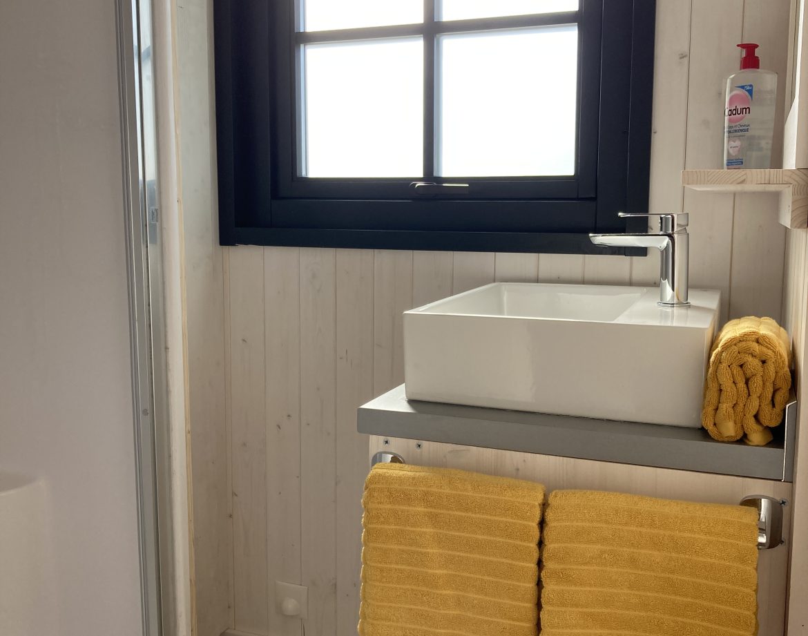 Salle de bain dun hébergement insolite en Languedoc-Roussillon avec serviettes jaunes.