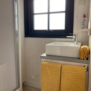 Salle de bain dun hébergement insolite en Languedoc-Roussillon avec serviettes jaunes.
