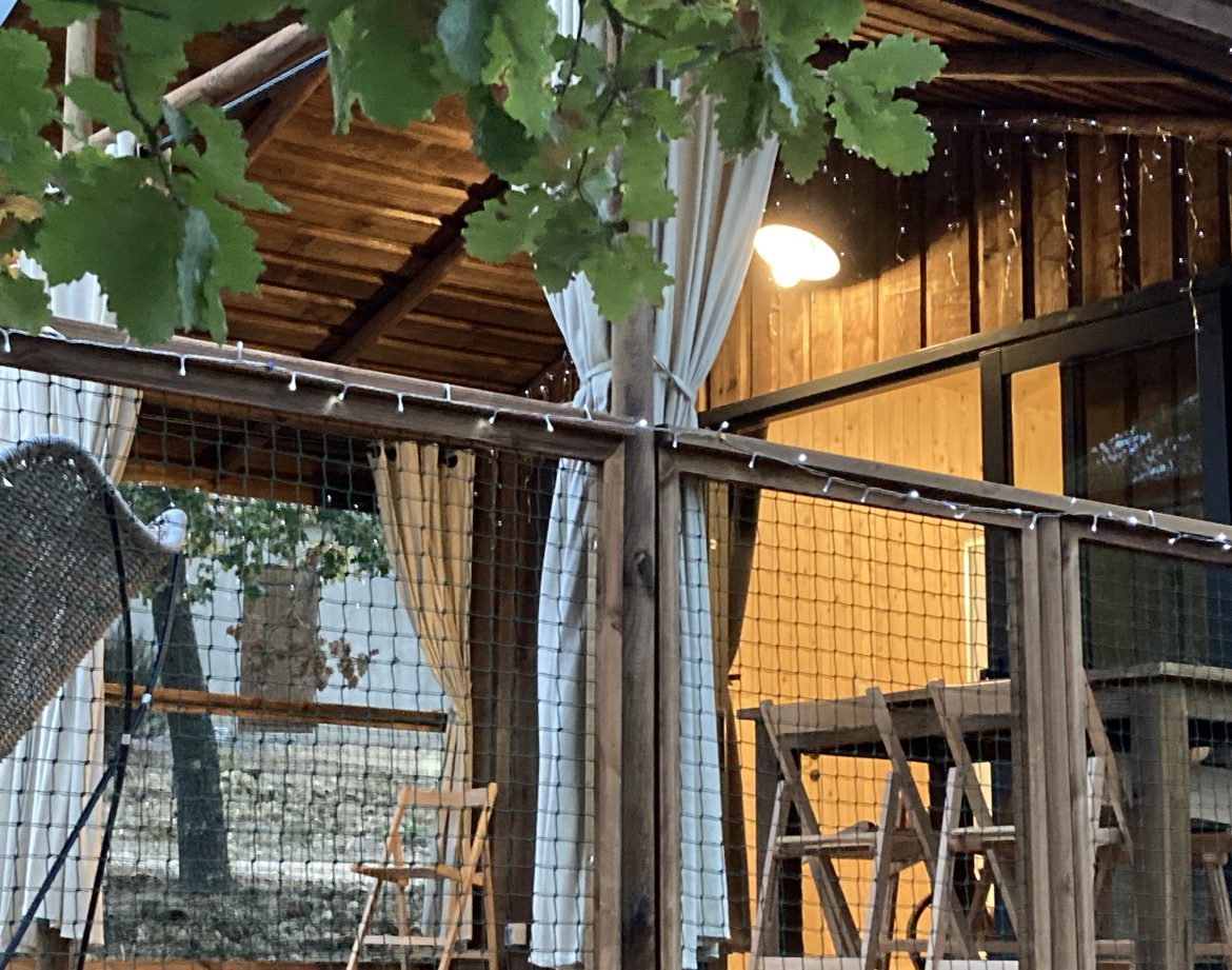 Cabane en bois avec rideaux blancs et éclairage doux, au cœur du Languedoc-Roussillon.
