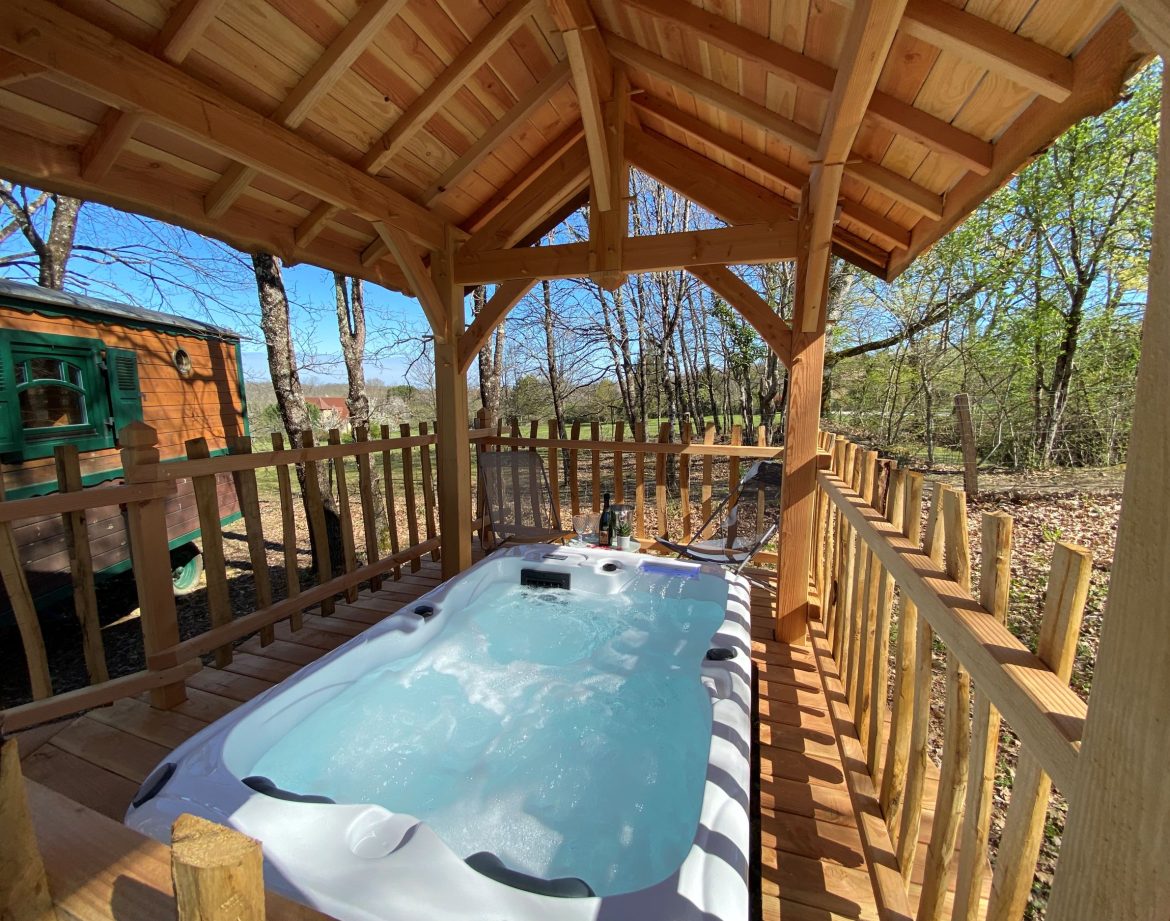 Hébergement insolite en Aquitaine : chalet en bois avec jacuzzi sous abri.