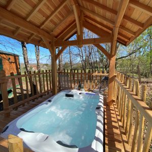Hébergement insolite en Aquitaine : chalet en bois avec jacuzzi sous abri.