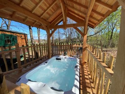 Hébergement insolite en Aquitaine : chalet en bois avec jacuzzi sous abri.