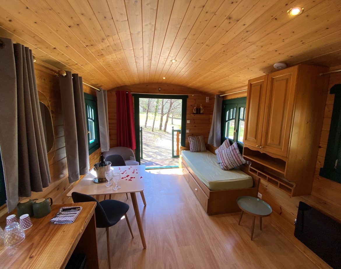Intérieur chaleureux dune roulotte en Aquitaine, avec un coin salon lumineux.