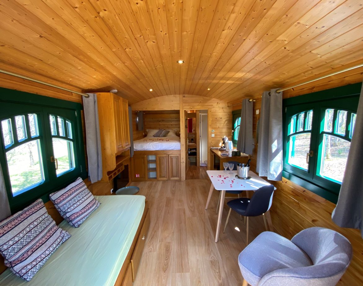 Hébergement insolite en Aquitaine : charmante roulotte en bois avec fenêtres colorées.