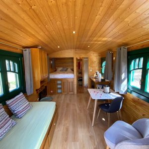 Hébergement insolite en Aquitaine : charmante roulotte en bois avec fenêtres colorées.