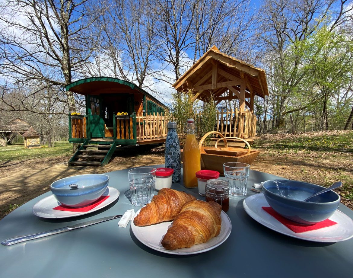 Roulotte en Aquitaine avec petit-déjeuner et vue sur un abri en bois.