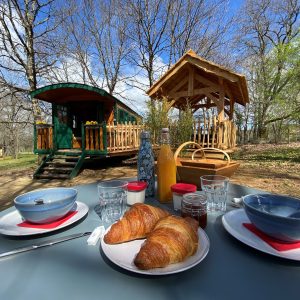 Roulotte en Aquitaine avec petit-déjeuner et vue sur un abri en bois.