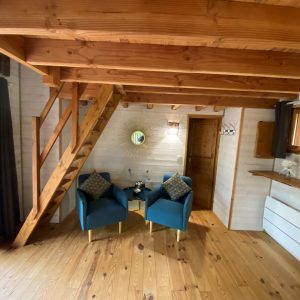 Cabane en bois en Aquitaine, avec un intérieur chaleureux et des fauteuils bleus.
