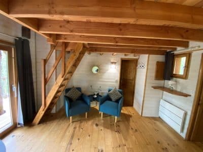 Cabane en bois en Aquitaine, avec un intérieur chaleureux et des fauteuils bleus.