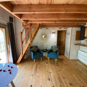 Cabane perchée en Aquitaine, avec un intérieur en bois et des fauteuils bleus.