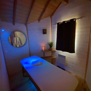 Hébergement insolite en Aquitaine : un espace bien-être avec table de massage et éclairage apaisant.