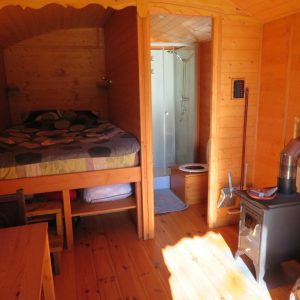 Cabane en bois en Bretagne, avec lit en hauteur et poêle à bois chaleureux.