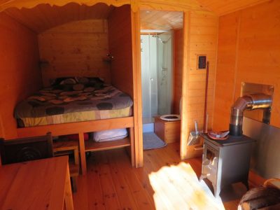 Cabane en bois en Bretagne, avec lit en hauteur et poêle à bois chaleureux.