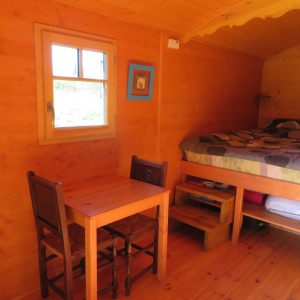 Cabane en bois en Bretagne, avec un lit douillet et une table en bois.