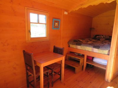 Cabane en bois en Bretagne, avec un lit douillet et une table en bois.