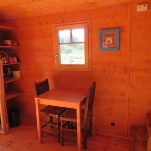 Intérieur chaleureux dun hébergement insolite en Bretagne, avec table en bois et fenêtre.