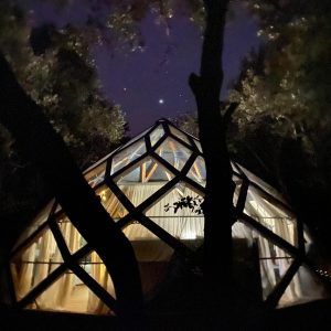 Hébergement insolite en forme de dôme, illuminé sous un ciel étoilé.