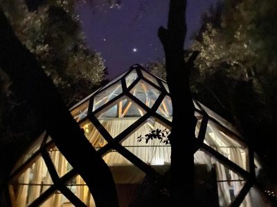 Hébergement insolite en forme de dôme, illuminé sous un ciel étoilé.