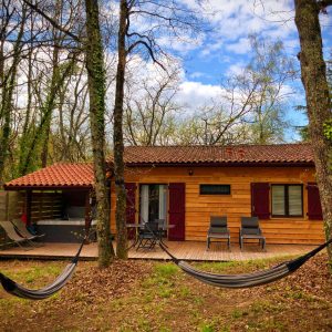 Cabane en bois à Midi-Pyrénées, entourée darbres, avec hamacs relaxants.
