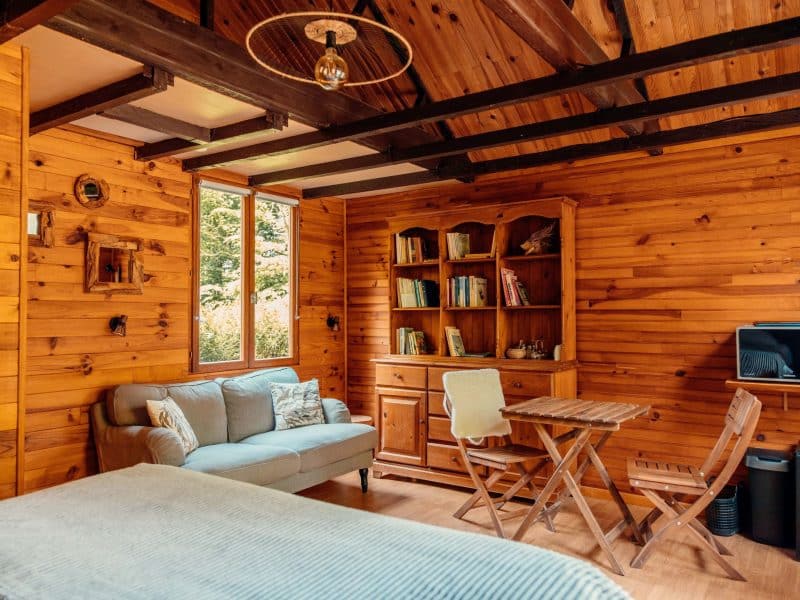 Cabane en bois chaleureuse avec un coin salon et une vue sur la nature.