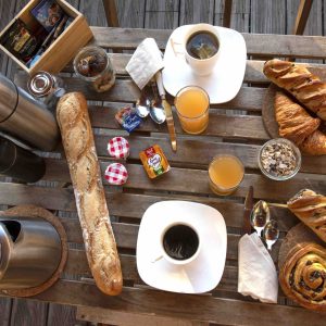 Petit-déjeuner copieux dans un hébergement insolite en Hauts-de-France, sur une table en bois.