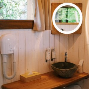Hébergement insolite à Hauts-de-France : salle de bain avec lavabo en pierre et miroir rond.