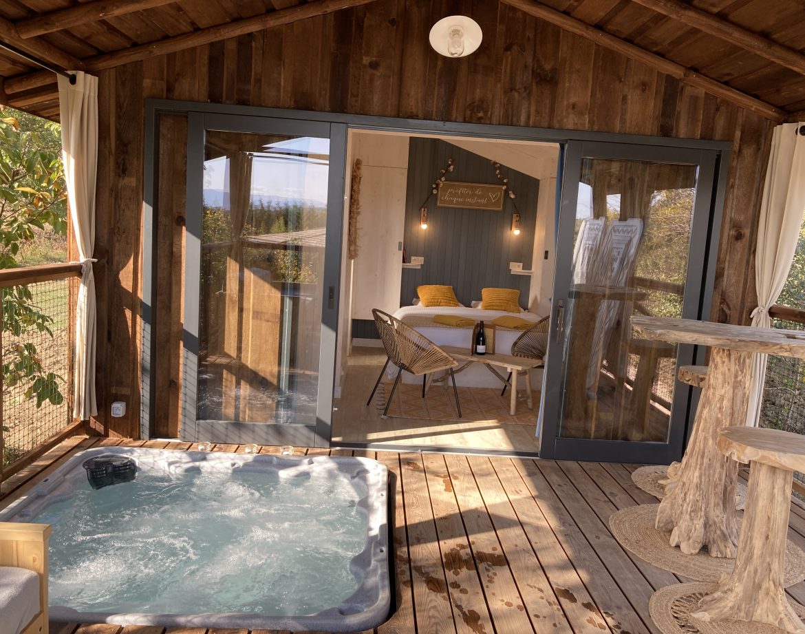 Cabane en bois avec jacuzzi, vue sur la nature, ambiance cosy et chaleureuse.