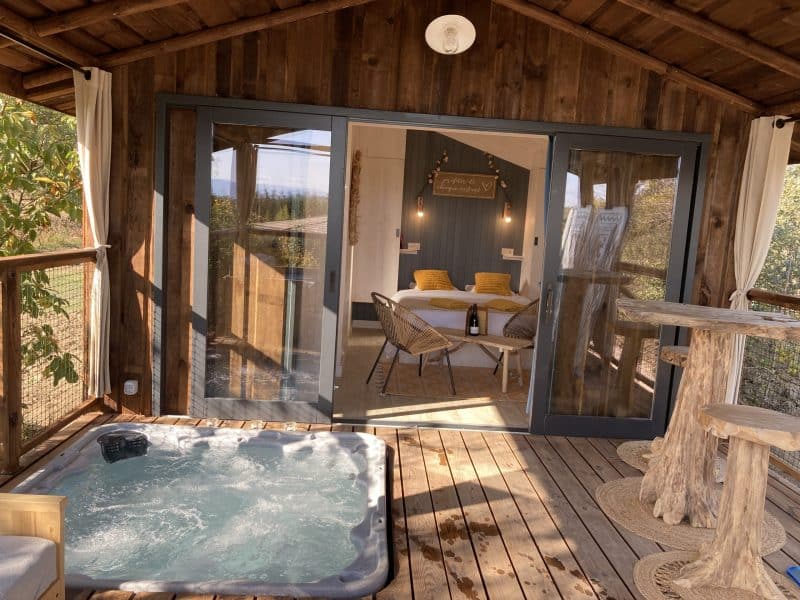 Cabane en bois avec jacuzzi, vue sur la nature, ambiance cosy et chaleureuse.